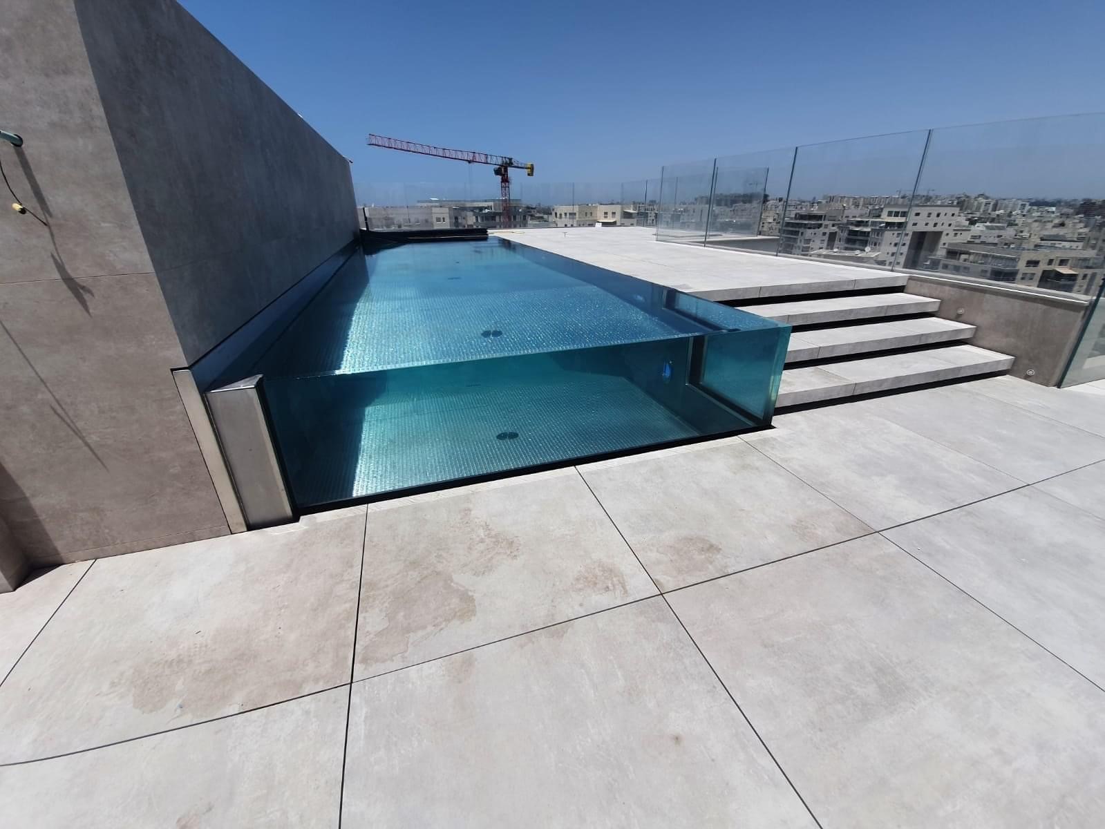 Moderný bazén so sklenenými stenami na terase domu v Tel Avive